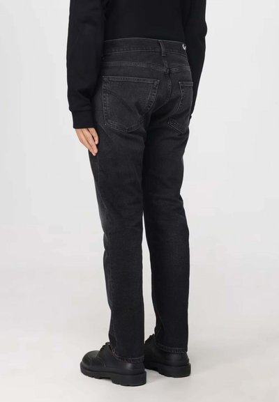 Jeans en denim noir avec une coupe droite, dotés de poches arrière et d'une texture légèrement délavée. Portés avec des chaussures noires.