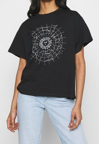 Camiseta de algodón negra con un estampado gráfico blanco de un sol y un patrón de constelaciones, con un ajuste relajado y mangas cortas.