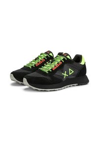 Zapatillas deportivas negras con acentos verdes y rojos, material de malla y gamuza, logo triangular, cordones texturizados y suela de goma gris.