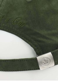 Grüne Wildlederkappe mit gesticktem Text. Verfügt über einen Metallverschluss, der mit einem Fleur-de-Lis-Symbol geschmückt ist. Glatte Textur, gebogene Form, verstellbarer Riemen.