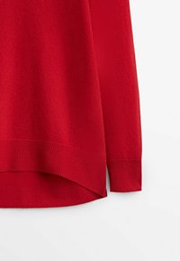 Pull en tricot rouge avec des poignets et un ourlet côtelés, doté d'un ourlet arrière légèrement plus long et d'une texture douce. Design simple, sans motifs ni accents supplémentaires.