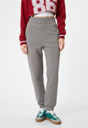 Grijze joggingbroek met een elastische tailleband en geribde boorden, gecombineerd met teal en grijze sneakers met witte veters.