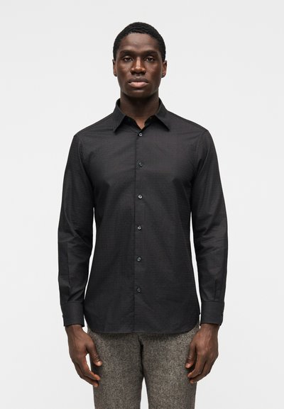 Camisa negra abotonada con un cuello estructurado, mangas largas y una textura sutil. Cerrada con botones oscuros, diseñada para un ajuste entallado.