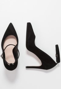 Svarta mockahöga klackskor med spetsig tå, ankelrem och en smal klack. Mjukt innertyg och utkarvade sidor.