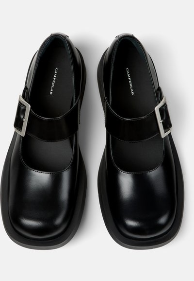 Paar schwarze Mary Jane Schuhe aus Leder mit quadratischen Zehen, silbernen Schnallen, dicken schwarzen Sohlen und Camperlab-Branding innen.
