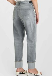 Lichtgrijze spijkerbroek met een losse pasvorm, omgeslagen boorden en traditionele achterzakken met een subtiel logodesign.