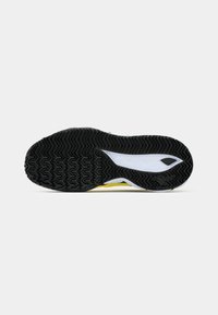 La semelle de chaussure présente une surface en caoutchouc noir texturé, des accents jaunes et blancs, et un design épuré avec un logo distinct près du talon.