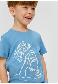 Lichtblauwe katoenen t-shirt met een witte afbeelding van een haai met een open mond, tekst "Waves Catcher," en korte mouwen. Gladde textuur.