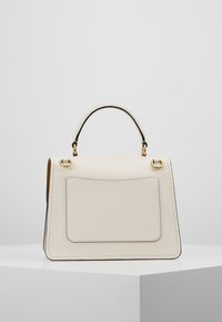 Krämfärgad läderhandväska med strukturerad design, ovandelshandtag, guldhardware och en framficka. Förstärkt sömnad längs kanterna.