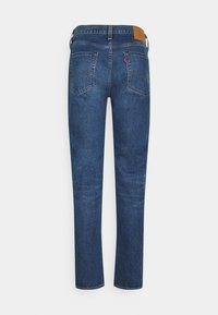 Jeans de mezclilla azul oscuro con un diseño de pierna recta, estilo de cinco bolsillos y una etiqueta de cuero en la cintura con detalles de la marca.
