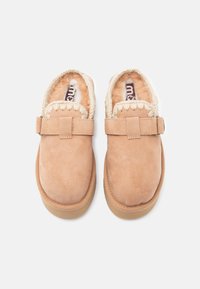 Tan suède instap schoenen met een zachte, donzige binnenkant en een geweven accent rond de kraag. Voorzien van een band en gesp voor aanpassing.