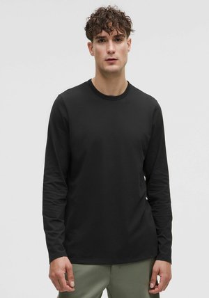 Black long-sleeve t-shirt made of lightweight fabric, featuring a round neckline and simple design, worn with olive green pants.