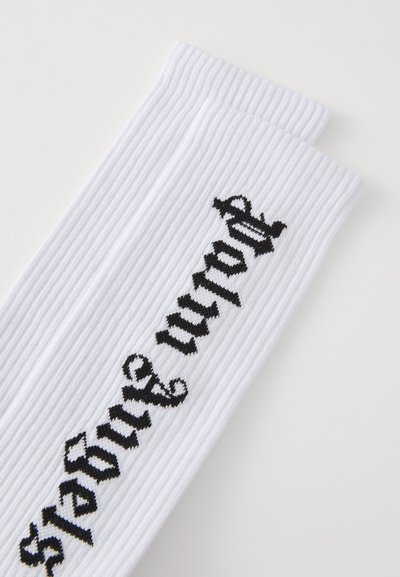 Sosete albe cu dungi, cu text negru care spune "tu contezi." Textul este poziționat pe latură, având un material texturat și o formă tradițională de șosete.