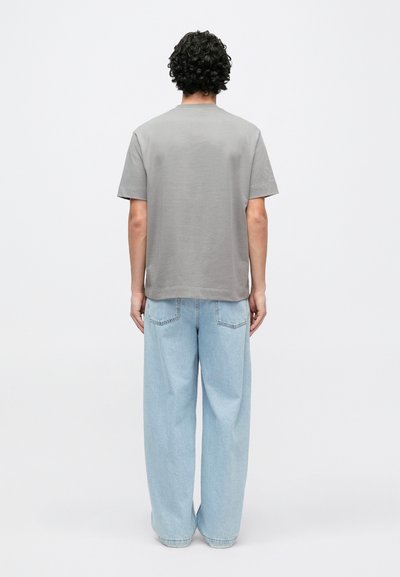 T-shirt cinzenta de manga curta com corte reto, combinada com jeans de perna larga azul claro. Textura suave, design minimalista, sem padrões visíveis.