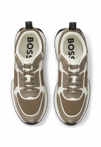 Pari kengät mesh väreissä beige ja ruskea, joissa on valkoisia yksityiskohtia, mustat kantanauhat, brändätyt sisäpohjat ja siististi asetellut nauhat.