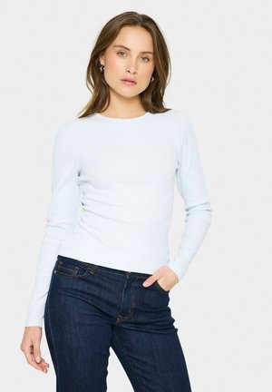 Ljust blå långärmad ribbad topp med rund hals, tillsammans med mörkblå jeans, som visar en kroppsnära design och slät textur.