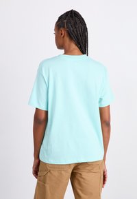 Lyseblå bomulds T-shirt med korte ærmer og rund hals. Glat tekstur og afslappet pasform, vist fra ryggen.