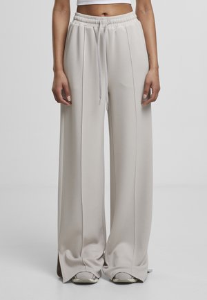 Pantalon de survêtement large et gris clair avec une taille élastique et un cordon de serrage, présentant une texture lisse et des coutures latérales.