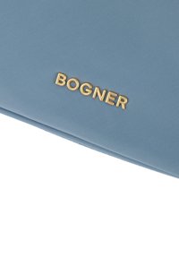 Ljusblå väska i tyg med texturerad yta och guld "BOGNER"-logotyp. Designen är minimalistisch med rena linjer.