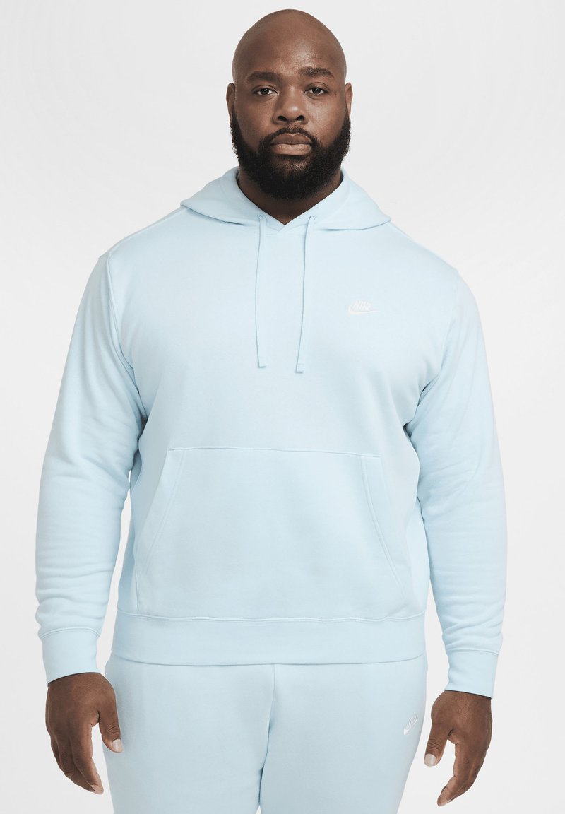 Sudadera azul claro hecha de tela suave, con un bolsillo frontal y capucha con cordón. Pequeño logo blanco de Nike en el pecho.