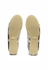 Chaussures de sport légères avec une semelle crème texturée, ornées d'accents métalliques argentés et noirs. Partie supérieure lisse avec un motif géométrique sur le côté.