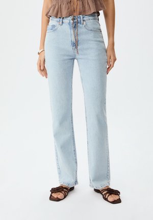 Jeans taille haute bleu clair avec une coupe droite, comportant cinq poches, des rivets en cuivre et une finition légèrement délavée.