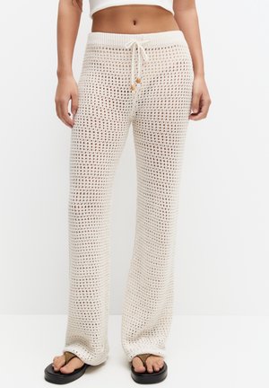Pantalons larges en tricot couleur écrue, présentant un tissage ouvert à motifs, une taille élastique avec cordon de serrage et une coupe décontractée.