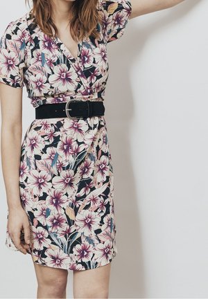 Abito floreale con fondo nero e grandi fiori rosa e bianchi. Design avvolgente con maniche corte e una cintura nera in vita.