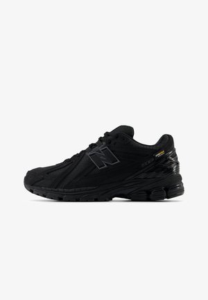 Baskets de sport noires avec dessus texturé, semelle matelassée, lacets, et marque en tissu Cordura sur le côté.