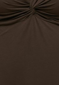 Tissu marron avec un nœud central créant des plis rassemblés sur une surface textile lisse.