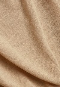 Tissu beige avec une texture lisse et douce et des plis délicats mettant en valeur le matériau tissé.