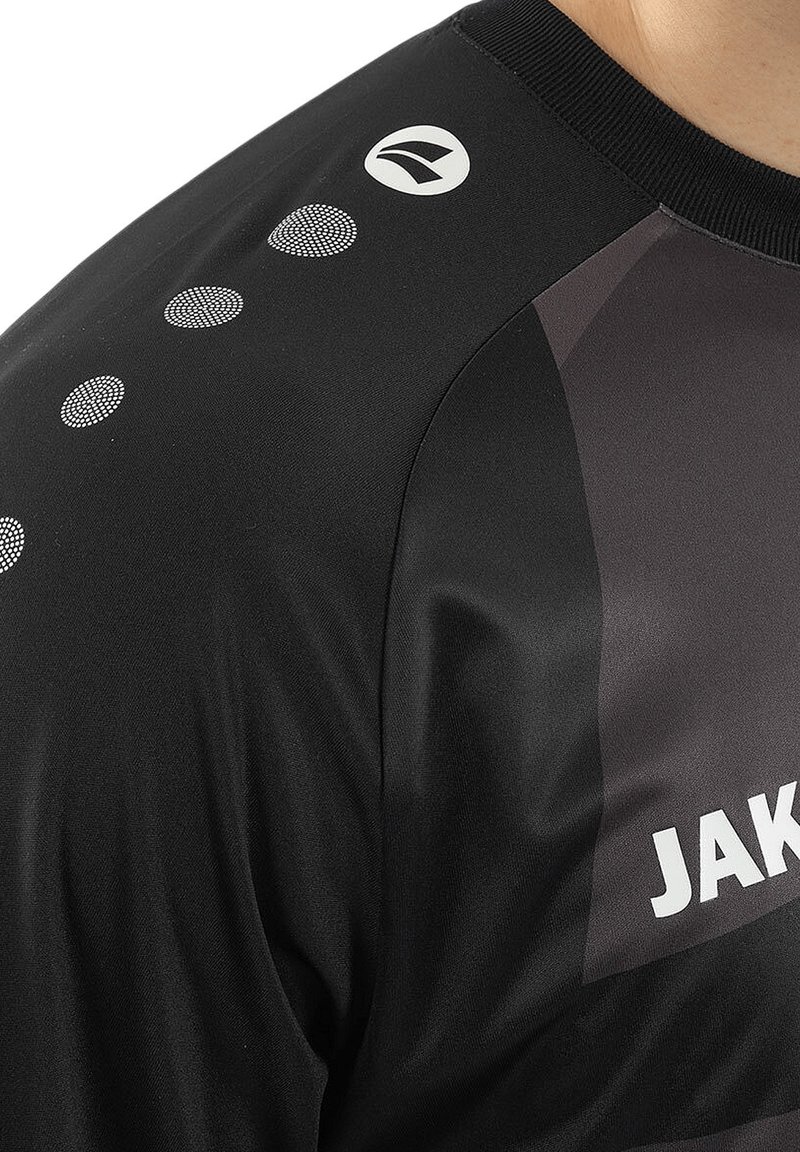 Schwarzes Sportshirt mit glatter Textur, mit grauem Akzent und reflektierenden Punkten entlang des Ärmels. Logo auf der Schulter gedruckt.