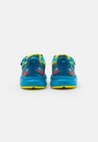 Scarpe da ginnastica blu con un upper testurizzato, accenti gialli brillanti e una cinghia sicura. Presentano un design astratto e colorato sulla parte posteriore del tallone.