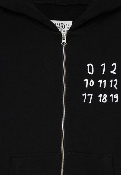 Schwarze Zip-Hoodie aus Baumwolle mit einem silbernen Reißverschluss und weißen grafischen Zahlen auf der linken Seite. Zwei Fronttaschen vorhanden.
