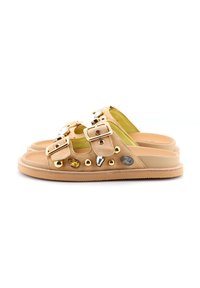 Infradito in suede color sabbia con suola piatta, dotate di due cinghie con fibbia e decorazioni in oro e gioielli sui lati.