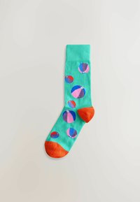 Green sock with orange heel and toe, decorated with colorful beach ball patterns in pink, blue, purple, and red on a light background.