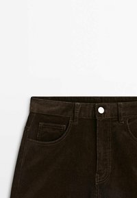Pantalon en velours côtelé marron avec une texture lisse, poches avant, passants de ceinture et fermeture à bouton argenté à la taille.