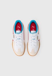 Białe sneakersy z beżowym zamszowym noskiem, czerwonym wnętrzem i turkusowymi akcentami, wyposażone w białe sznurówki i teksturowaną gumową podeszwę.
