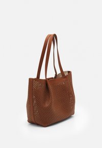 Brun perforeret tote taske med dobbelte håndtag, rektangulær form, struktureret overflade og åbent topdesign.