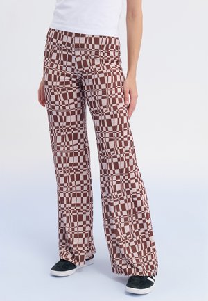 Brown and beige patterned flared pants made from a soft fabric, featuring a grid design and worn with black sneakers.