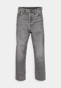 Světlé šedé džíny z denimu s designem s rovnými nohavicemi, pěti kapsami a viditelnou značkou poblíž pasu. Celkově vybledlá textura.