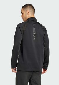 Zwarte sportieve pullover met een hoge kraag, voorzien van een gestructureerd zijontwerp, reflecterende "CLIMACOOL" branding en aansluitende mouwen.