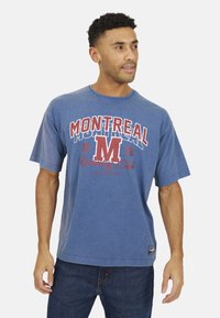 Blauwe katoenen t-shirt met "MONTREAL" grafiek in rood en wit, ronde hals, korte mouwen en een rechte zoom. Draagt het met donkere denim jeans.