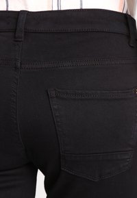 Zwarte denim jeans, met een aansluitend ontwerp, gemiddelde taillehoogte en klassieke achterzak. Glad materiaal met verstevigde stiksels.