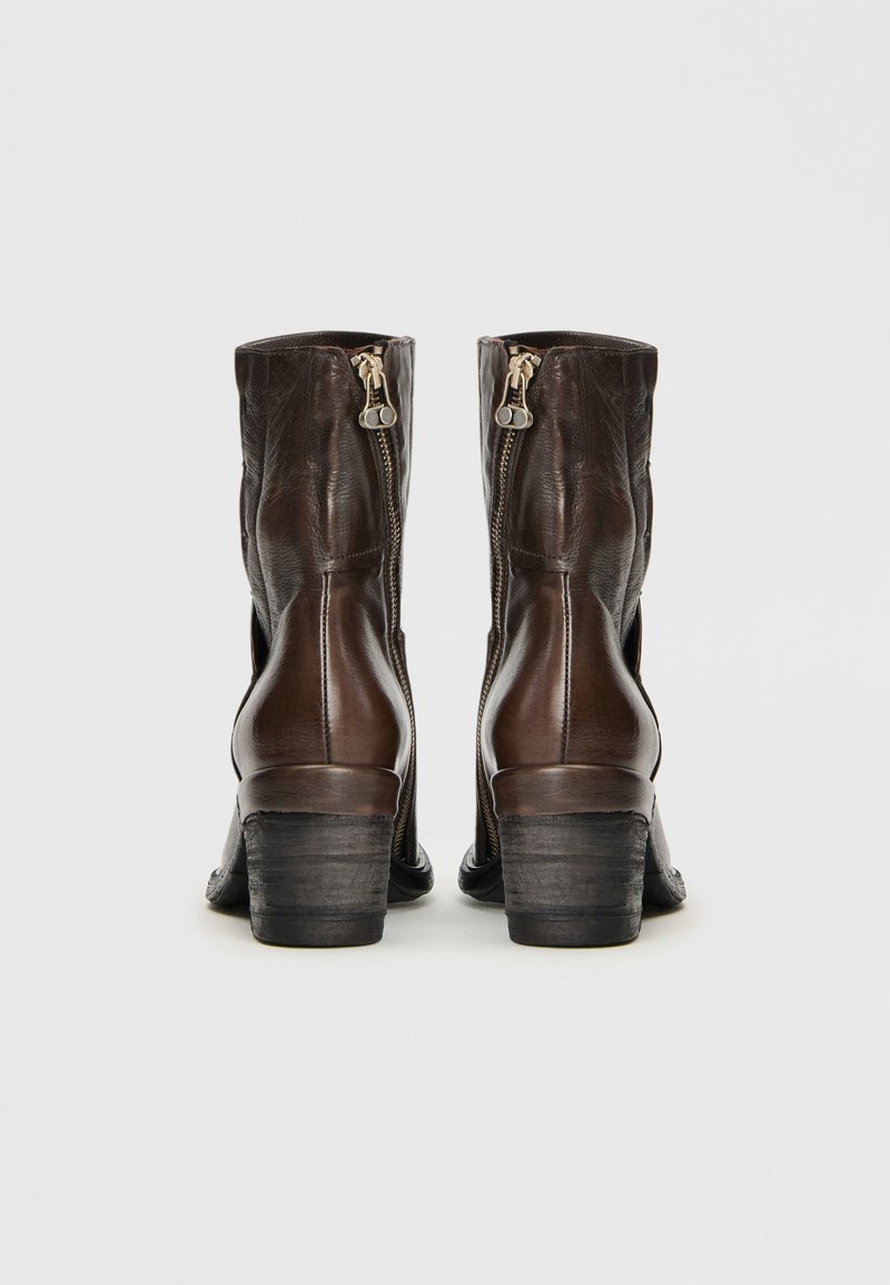 Stivali alla caviglia in pelle marrone con tacco medio a blocco, dotati di doppie cerniere laterali e dettagli di texture sottili.