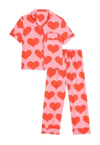 Conjunto de pijama de manga corta en tela rosa con grandes patrones de corazones rojos. Incluye una camiseta de botones con bolsillo y pantalones a juego con cintura elástica.