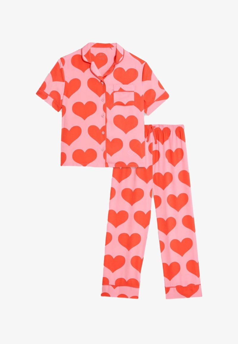 Conjunto de pijama de manga corta en tela rosa con grandes patrones de corazones rojos. Incluye una camiseta de botones con bolsillo y pantalones a juego con cintura elástica.