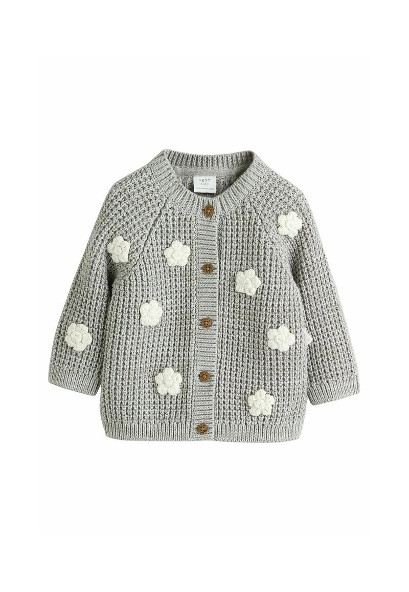 Gilet en tricot gris avec des appliqués floraux crème, col rond, manches longues, fermeture à boutons en bois, et bords-côtes au niveau des poignets et de l'ourlet.