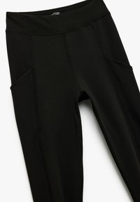 Leggings negros fabricados con un tejido elástico, que cuentan con bolsillos laterales, una cintura alta y costuras planas para comodidad y flexibilidad.