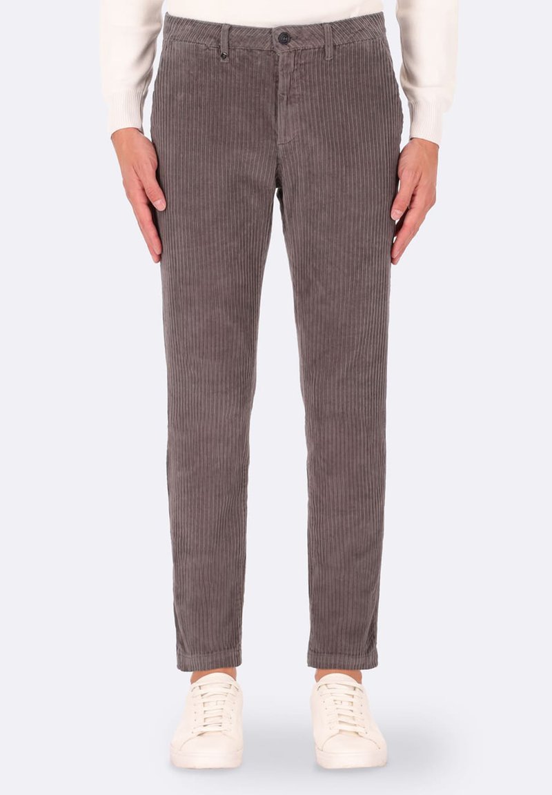 Pantaloni in velluto a coste grigi con righe verticali, design slim-fit, vita standard e chiusura con bottone, abbinati a sneakers bianche.